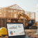 Contractor reviewing job costing and cash flow reports on a laptop at a construction site